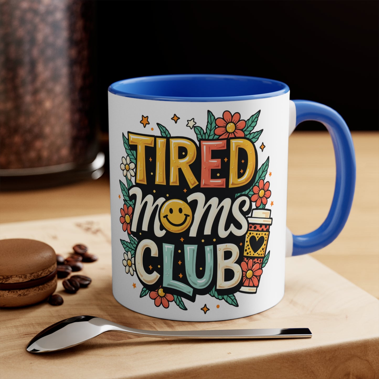 White mug with "Tired Moms Club" text, smiley face, and coffee cup design.
