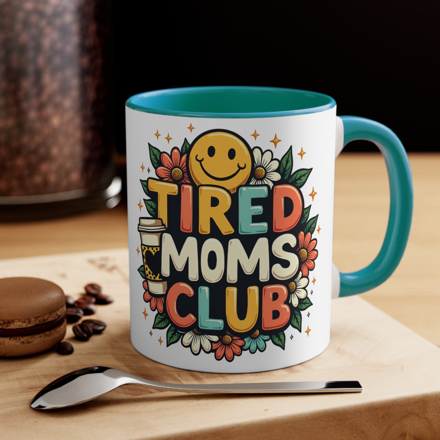 Mug with "TIRED MOMS CLUB" text, smiley face, coffee cup, and flowers.