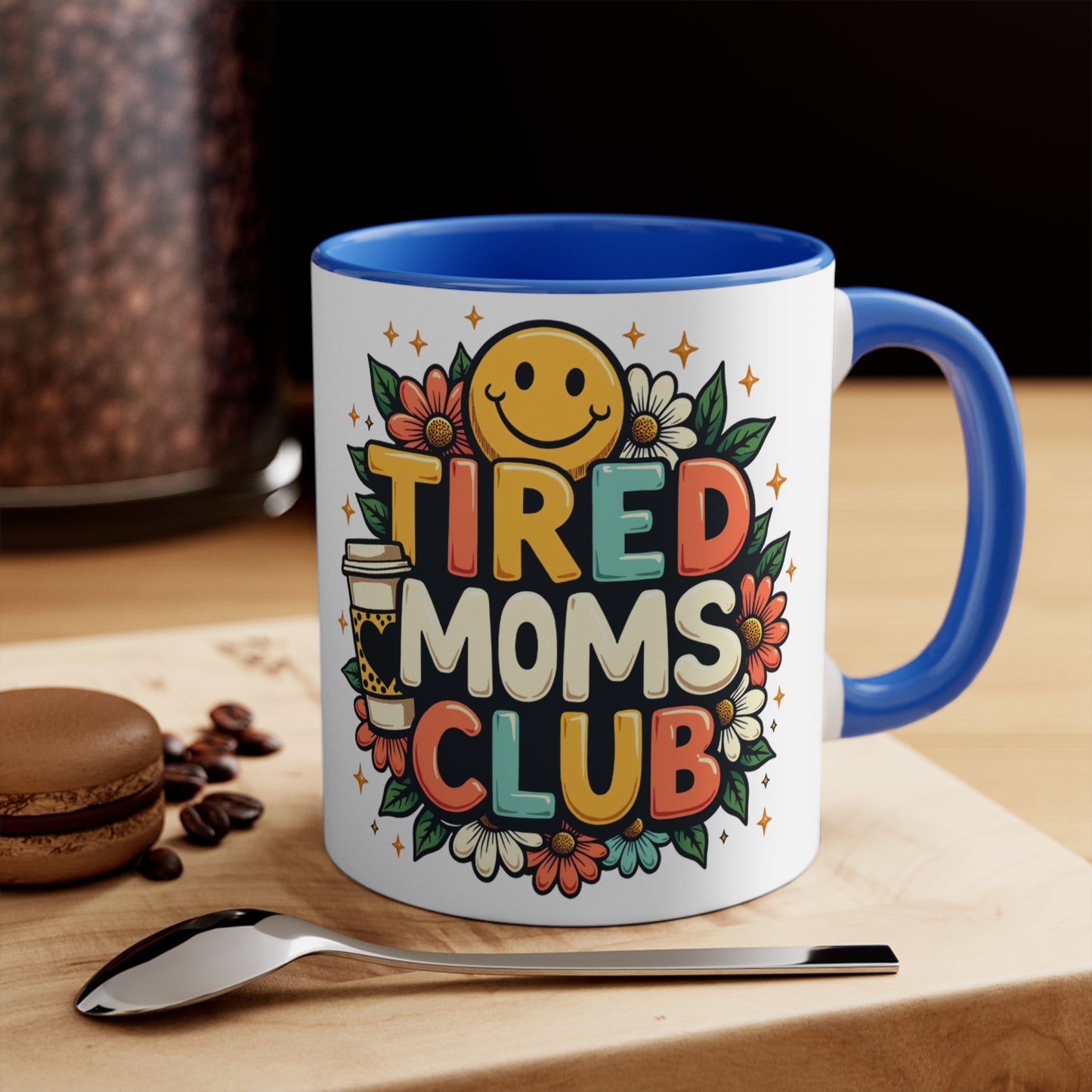 Mug with "TIRED MOMS CLUB" text, smiley face, flowers, and coffee cup graphic.